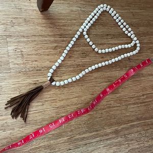 Cream “crackled” beads necklace with brown tassel at end.